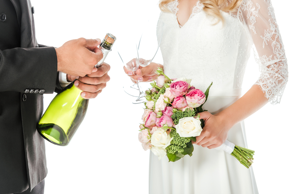 Une mariée avec un bouquet de fleur et une bouteille de champagne