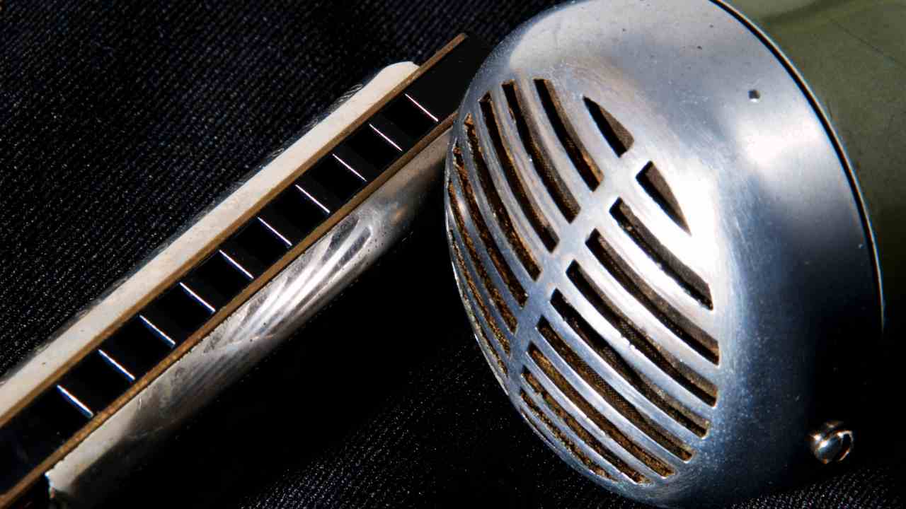 micro shure green bullet à côté d'un harmonica blues